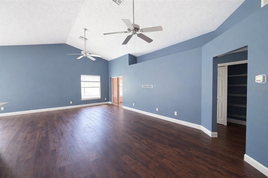 A spacious room with blue walls, vaulted ceilings, two ceiling fans, and dark wood flooring — 551 LAKE CHARLES DRIVE, DAVENPORT, FL