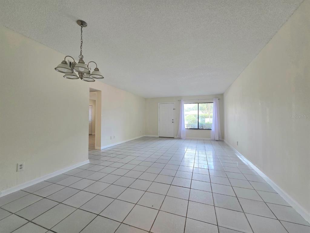 An empty room with white tile floors, a chandelier, and a white front door — 605 NORTHLAKE BOULEVARD UNIT 48, ALTAMONTE SPRINGS, FL