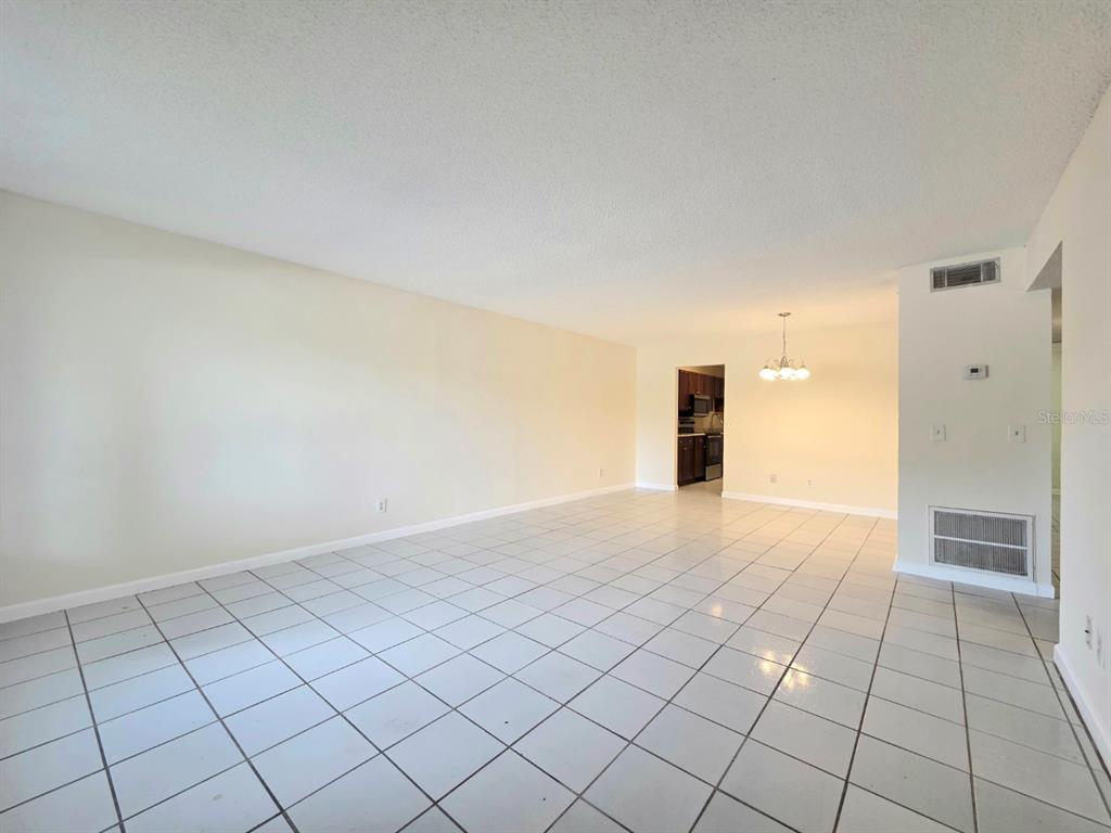 An open-concept living and dining area features white tiled floors and a neutral color palette — 605 NORTHLAKE BOULEVARD UNIT 48, ALTAMONTE SPRINGS, FL