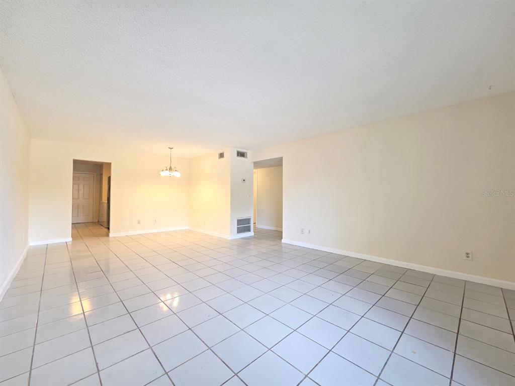 An open-concept living and dining area features white tiled floors and plain beige walls — 605 NORTHLAKE BOULEVARD UNIT 48, ALTAMONTE SPRINGS, FL