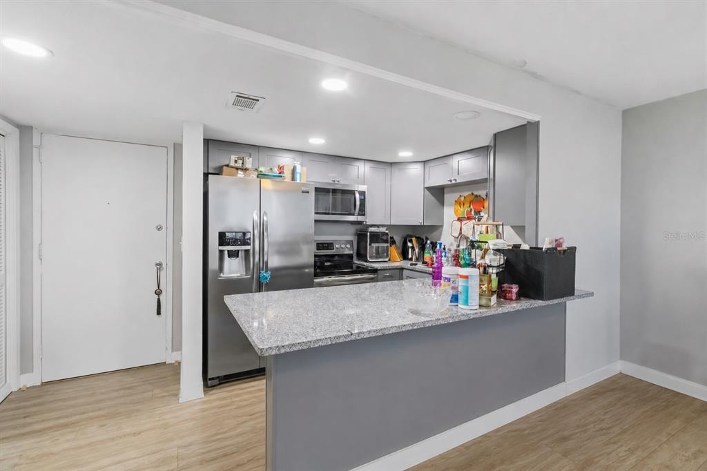 A kitchen features gray cabinets, stainless steel appliances, and a granite-topped breakfast bar — 4015 BAYSHORE BOULEVARD UNIT 12B, TAMPA, FL