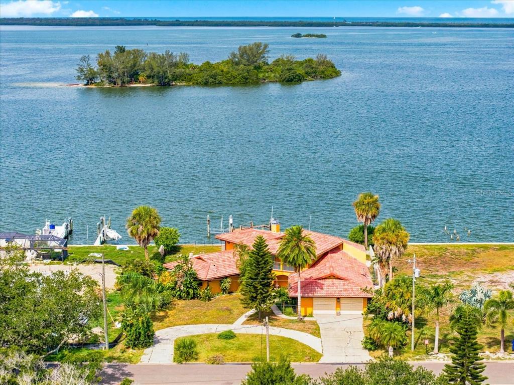 An aerial view of a waterfront house with a tile roof and a private dock — 111 SHORE DRIVE, DUNEDIN, FL