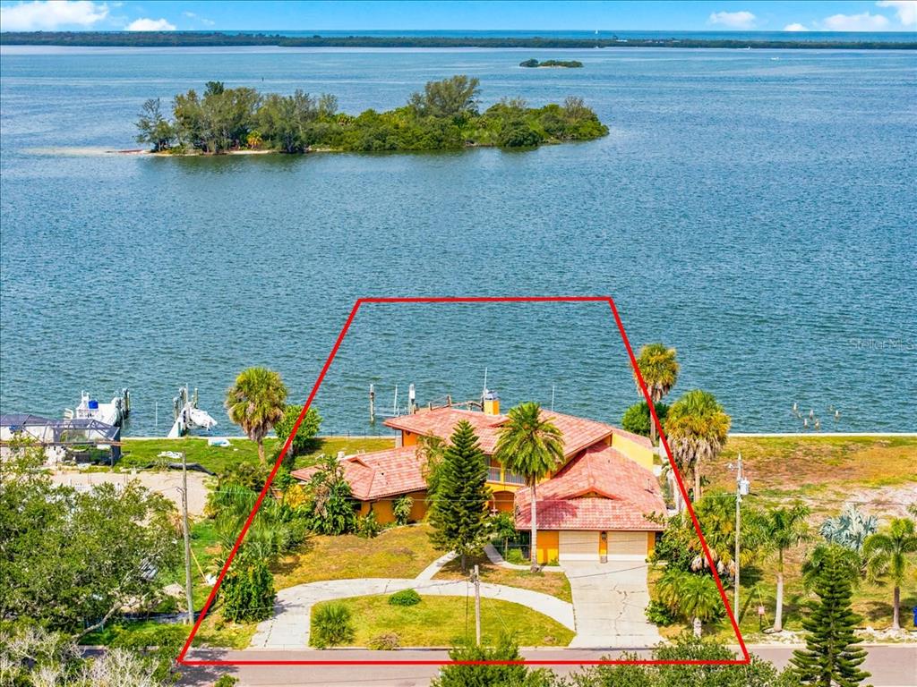 An aerial view of a waterfront house with a red-tiled roof and a large yard — 111 SHORE DRIVE, DUNEDIN, FL
