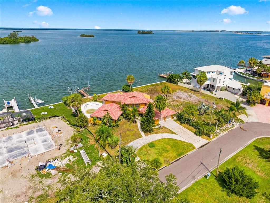 An aerial view shows a waterfront house with a red tile roof and a pool — 111 SHORE DRIVE, DUNEDIN, FL
