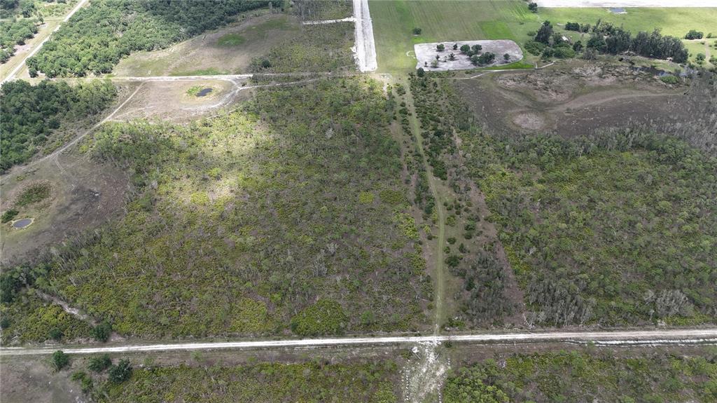 An aerial view shows a large, undeveloped plot of land with scattered trees and dirt paths — 21031 GRANVILLE ROAD, NORTH FORT MYERS, FL