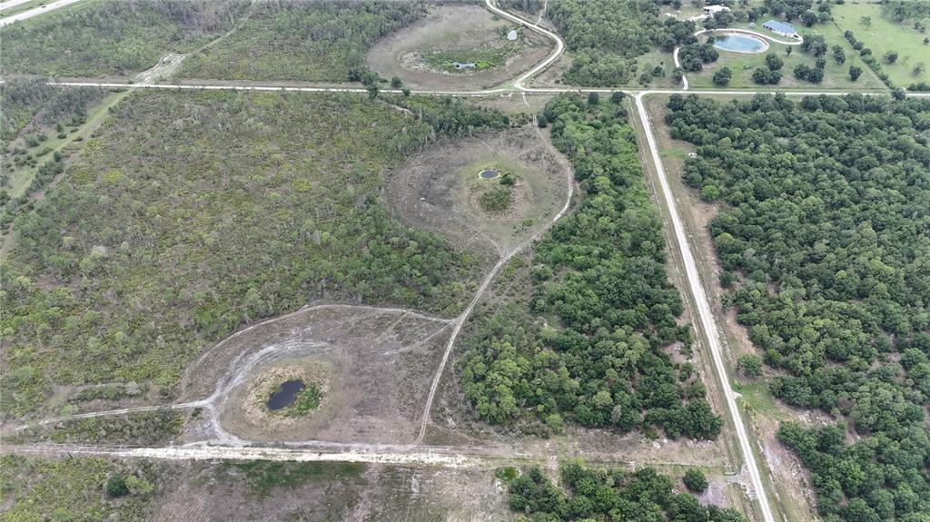 An aerial view shows rural land with scattered ponds, dirt paths, and dense wooded areas — 21031 GRANVILLE ROAD, NORTH FORT MYERS, FL