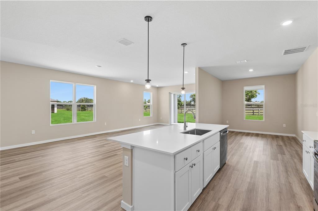 A kitchen island with a white countertop and sink sits in an open-concept living area — 4473 NW 37TH STREET ROAD, OCALA, FL