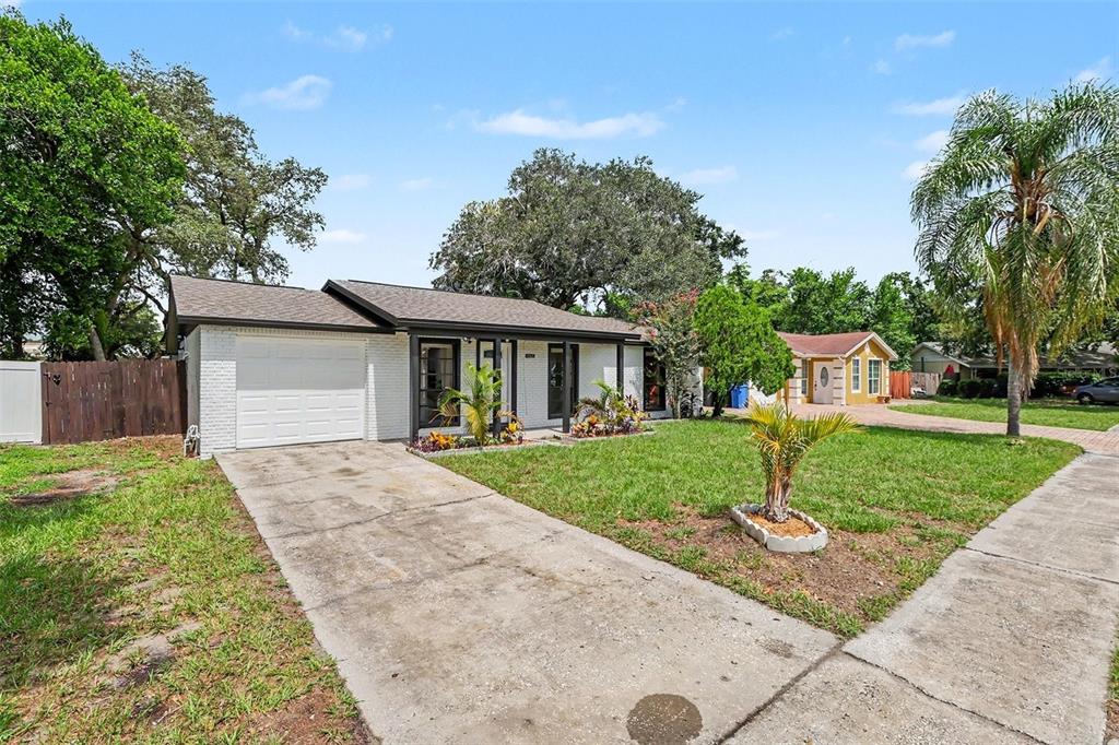 A single-story white brick house with a garage and a front lawn under a blue sky — 8253 GREENLEAF CIRCLE, TAMPA, FL