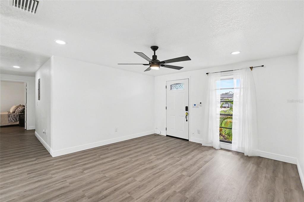 A living room with white walls, wood-look flooring, a ceiling fan, and a front door — 8253 GREENLEAF CIRCLE, TAMPA, FL