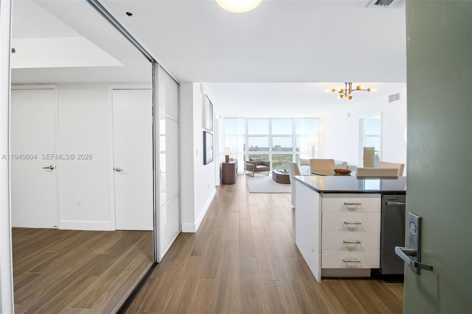A view from an entryway into a modern apartment with wood floors and floor-to-ceiling windows — 50 Biscayne Blvd # 3904, Miami FL 33132, MIAMI, FL