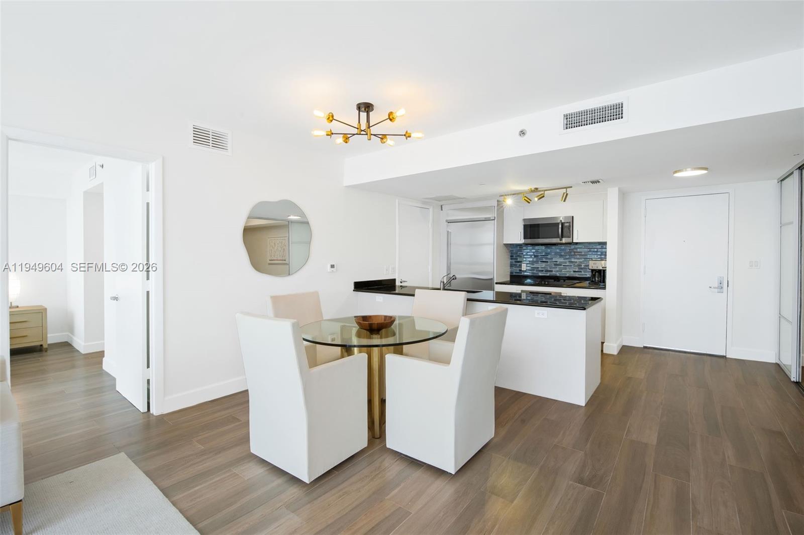 A dining area with a glass table and four chairs sits before an open kitchen — 50 Biscayne Blvd # 3904, Miami FL 33132, MIAMI, FL