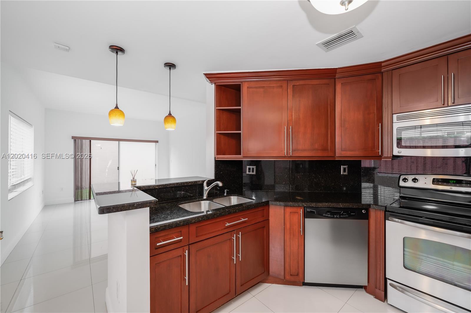 A kitchen features cherry wood cabinets, black granite countertops, and stainless steel appliances — 4668 SW 153rd Ct, Miami FL 33185, MIAMI, FL