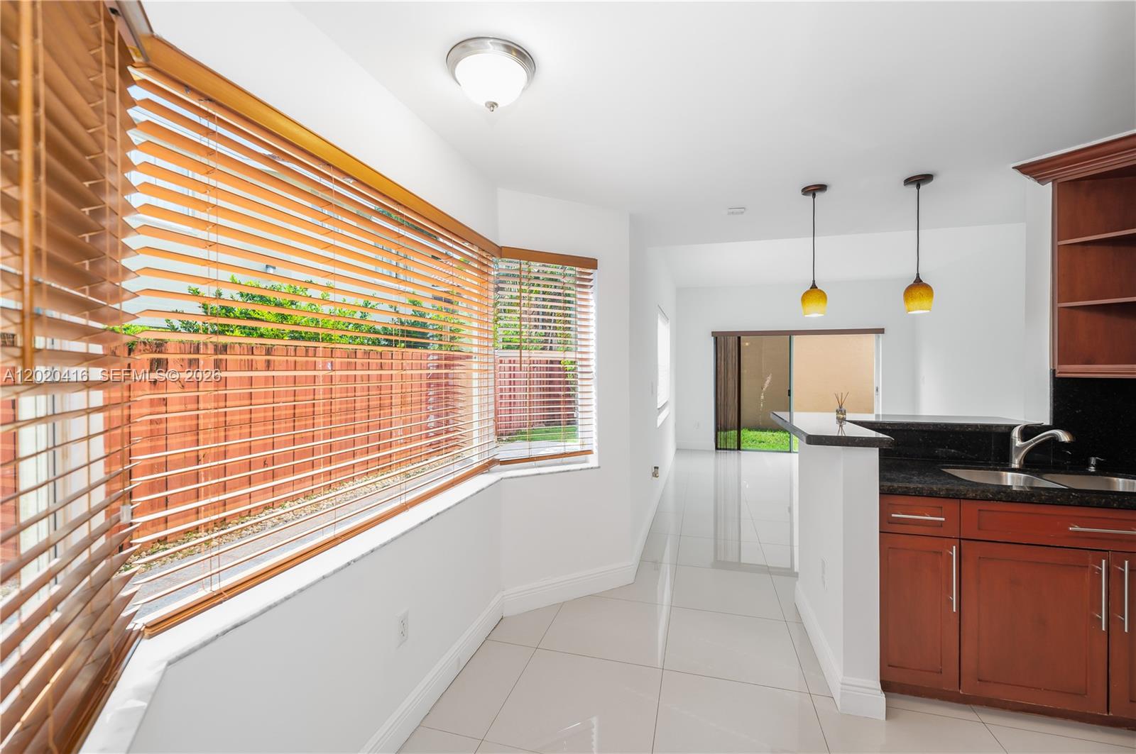 A kitchen area features dark wood cabinets, granite countertops, tile flooring, and a bay window — 4668 SW 153rd Ct, Miami FL 33185, MIAMI, FL