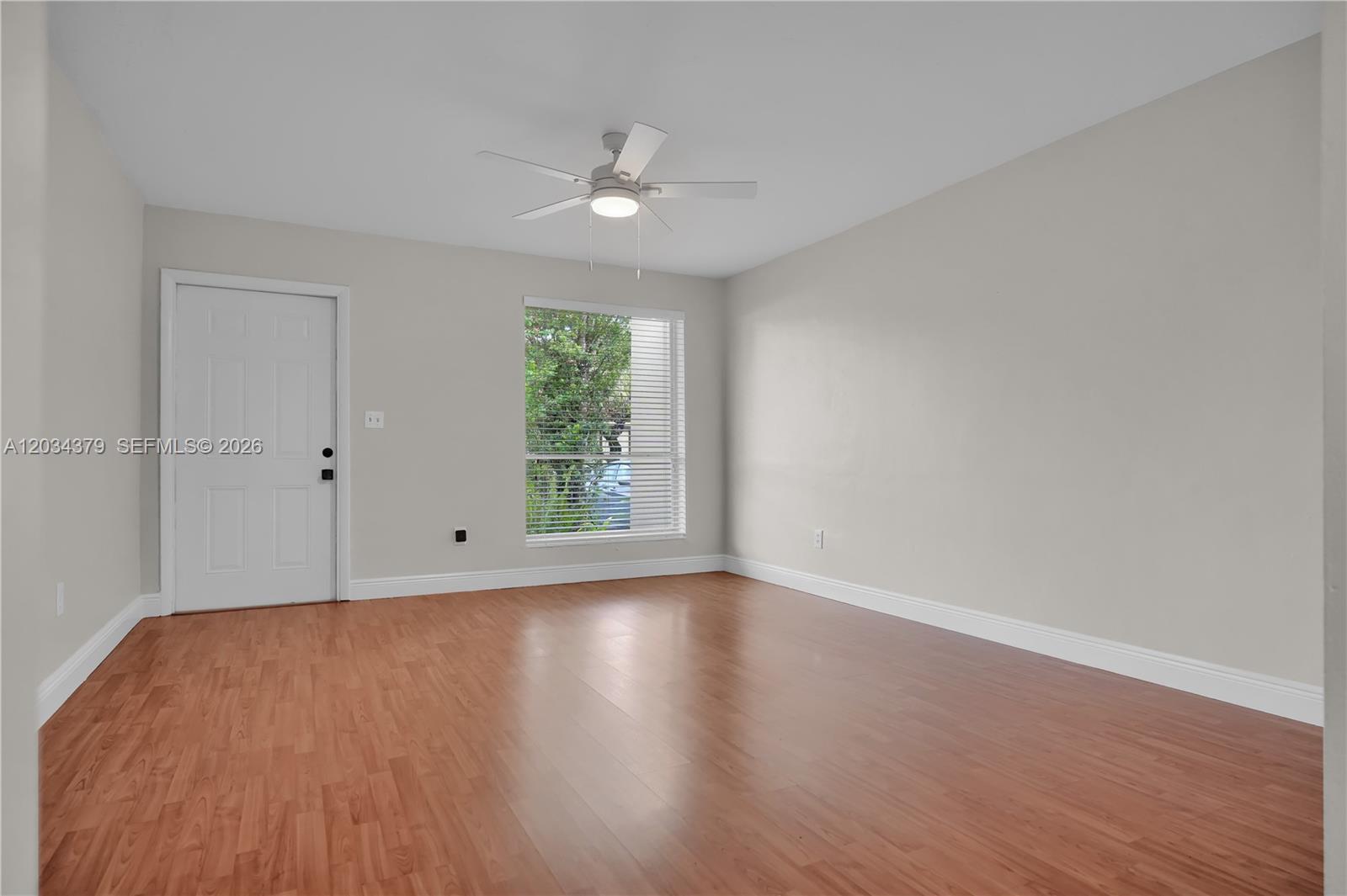An empty room features light-colored walls, wood-look flooring, a ceiling fan, and a window — 10953 SW 122nd Ct, Miami FL 33186, MIAMI, FL