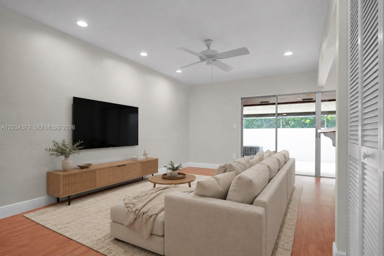 A living room features a wall-mounted television, a wooden media console, and a beige sectional — 10953 SW 122nd Ct, Miami FL 33186, MIAMI, FL