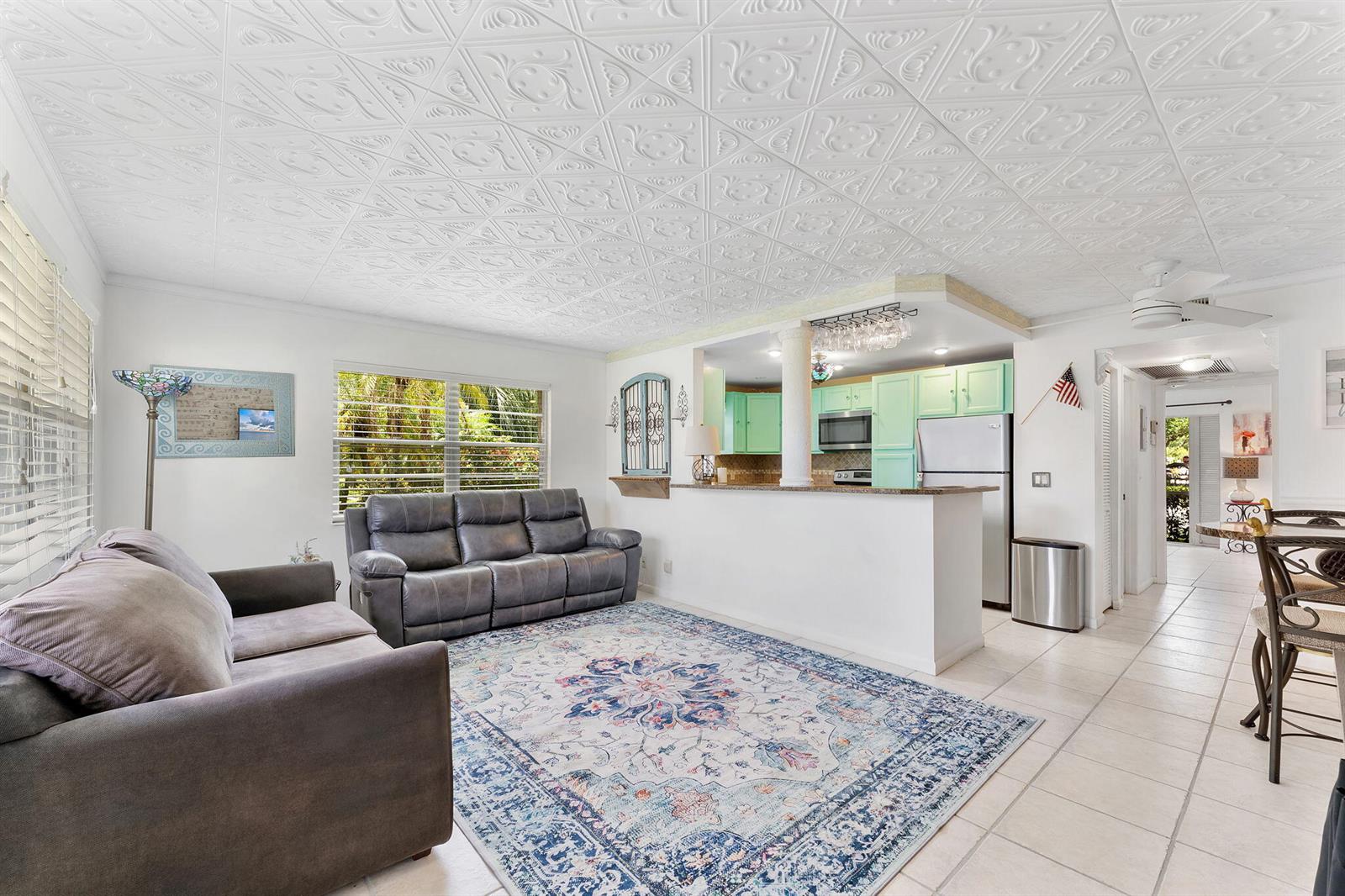 A living room with a patterned ceiling, gray sofa, and an open kitchen with mint cabinets — 269 S Ventnor S # 269, Deerfield Beach FL 33442, DEERFIELD BEACH, FL