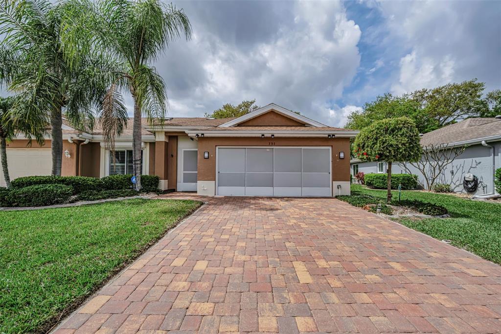 A single-story house with a paved driveway, a screened garage door, and palm trees — 737 MCCALLISTER AVENUE UNIT 265, SUN CITY CENTER, FL