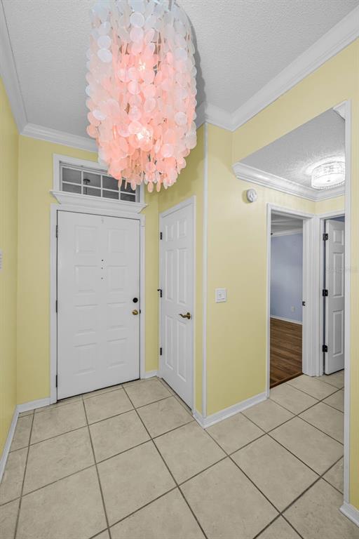 An entryway with yellow walls, tile flooring, a white door, and a pink chandelier — 737 MCCALLISTER AVENUE UNIT 265, SUN CITY CENTER, FL
