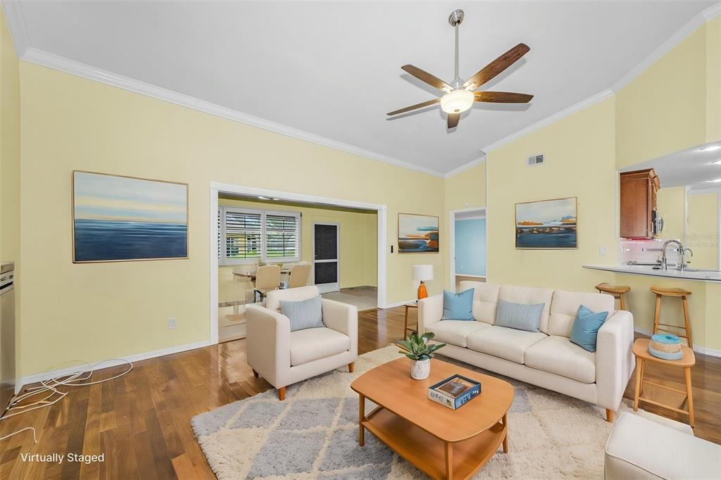 A living room with yellow walls, hardwood floors, a ceiling fan, and virtual staging furniture — 737 MCCALLISTER AVENUE UNIT 265, SUN CITY CENTER, FL