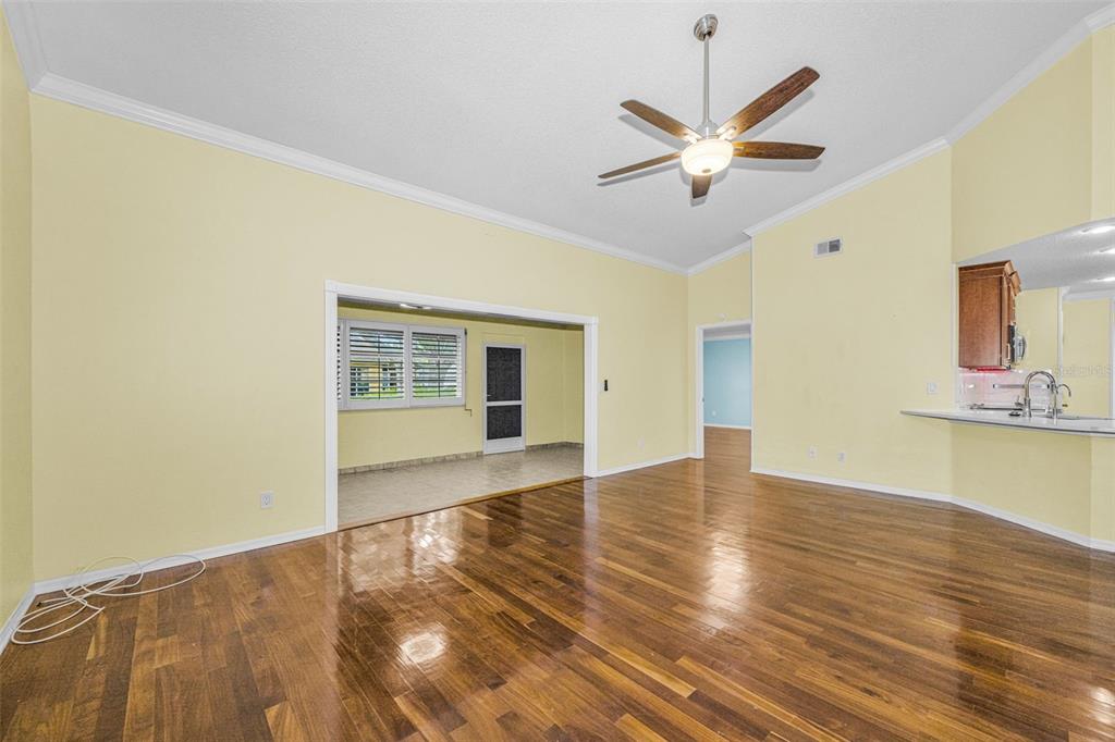 A living room with hardwood floors, yellow walls, a ceiling fan, and an adjacent kitchen — 737 MCCALLISTER AVENUE UNIT 265, SUN CITY CENTER, FL