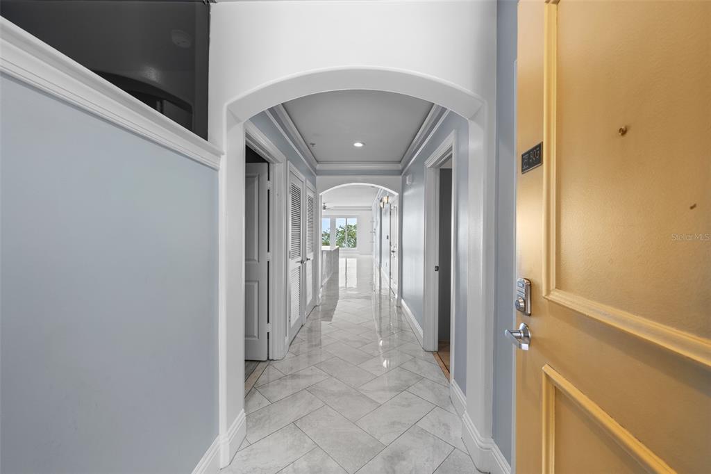 A hallway with light-colored tile flooring leads toward a windowed room under arched ceilings — 509 W BAY STREET UNIT 305, TAMPA, FL