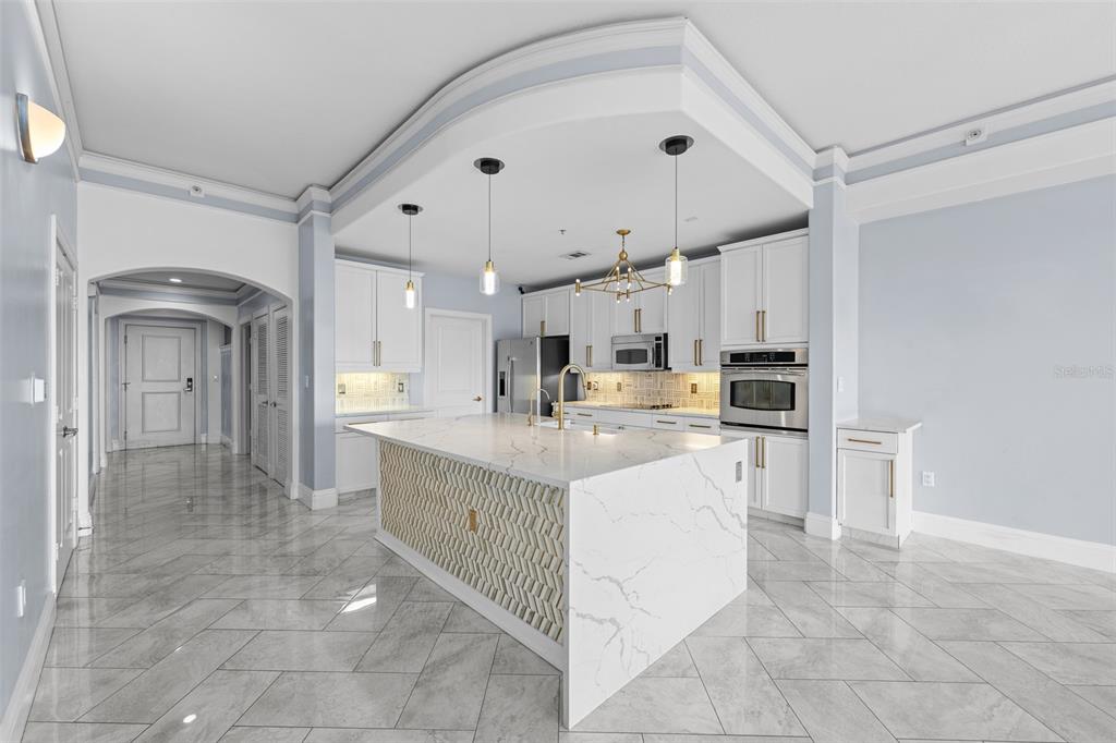 A modern kitchen features a large marble-topped island, white cabinetry, and light gray tile flooring — 509 W BAY STREET UNIT 305, TAMPA, FL