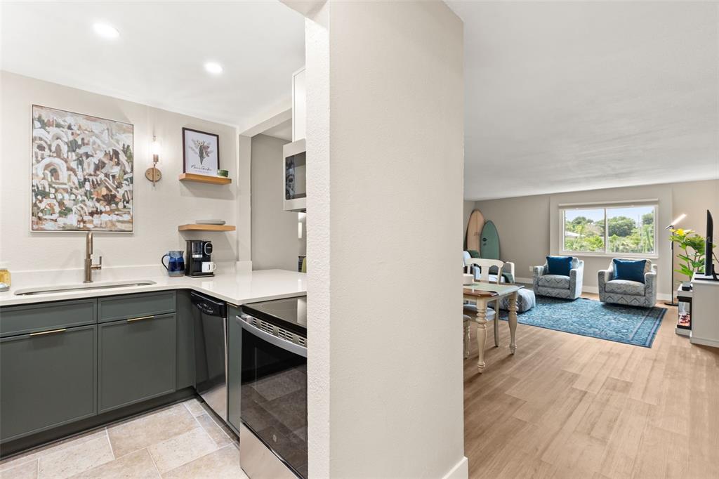 A kitchen with dark green cabinets and white countertops opens into a living area — 1928 CONWAY ROAD UNIT 40, ORLANDO, FL