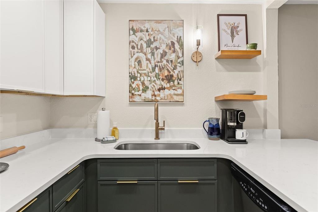 A kitchen area features dark green cabinets, white countertops, a stainless steel sink, and open shelving — 1928 CONWAY ROAD UNIT 40, ORLANDO, FL