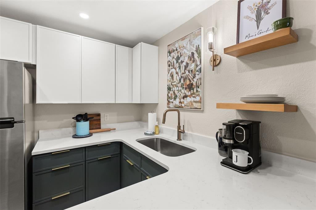 A kitchen features white upper cabinets, dark lower cabinets, a stainless steel sink, and floating shelves — 1928 CONWAY ROAD UNIT 40, ORLANDO, FL