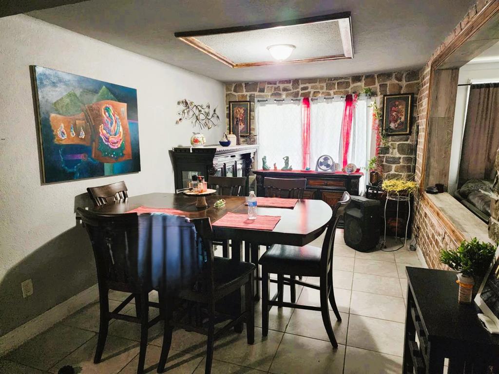 A dining room features a wooden table, stone accent wall, and a large abstract painting — 1149 HOLDEN AVENUE, ORLANDO, FL