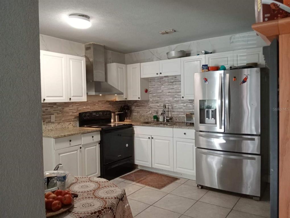 A kitchen with white cabinets, stainless steel appliances, granite countertops, and a tiled backsplash — 1149 HOLDEN AVENUE, ORLANDO, FL