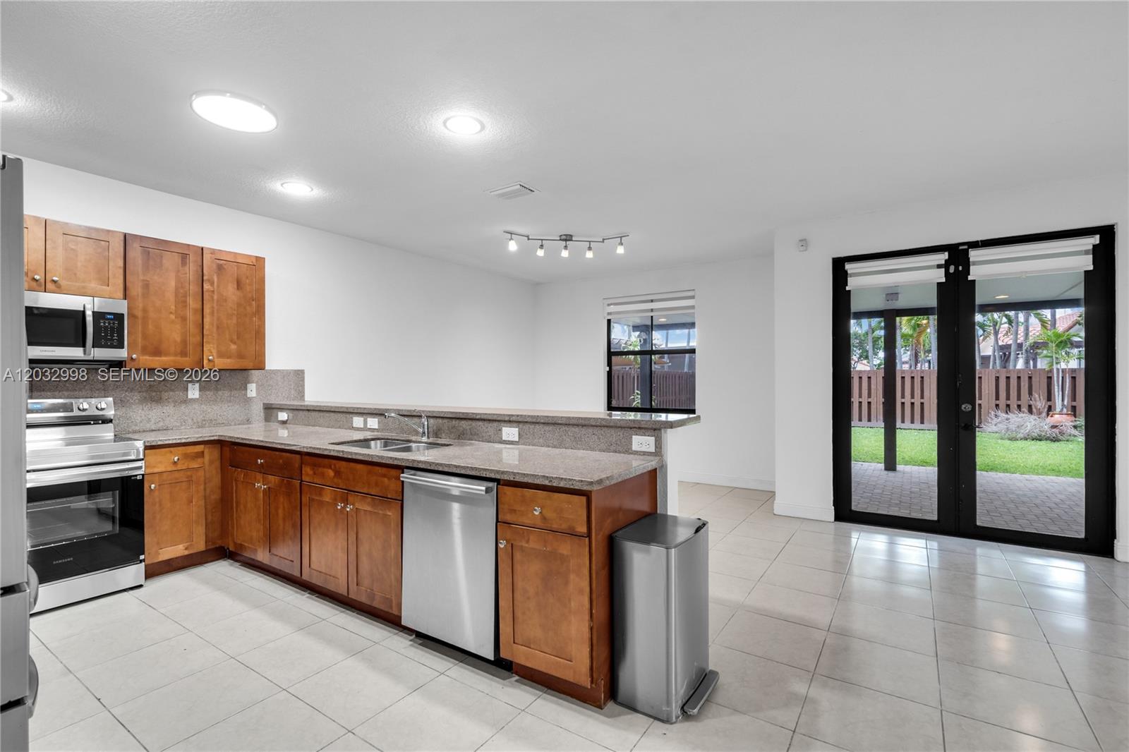 A kitchen with wood cabinets, granite countertops, stainless steel appliances, and glass doors to a patio — 9925 NW 10th St, Miami FL 33172, MIAMI, FL