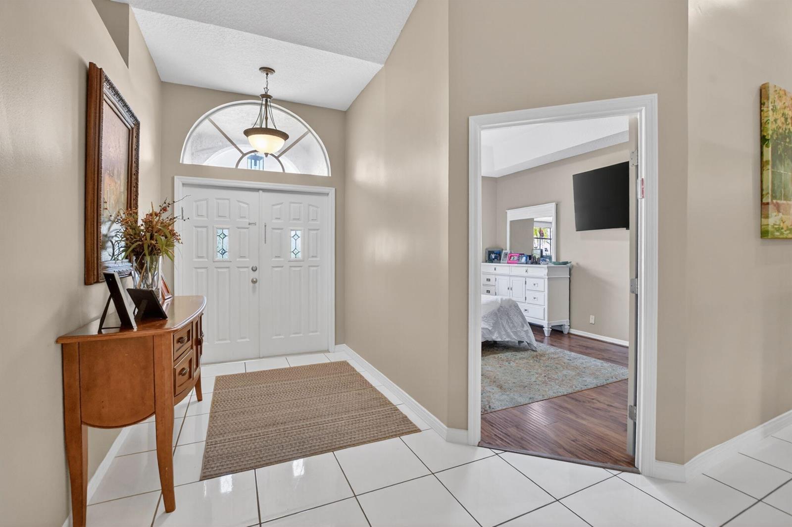A bright entryway with white tile floors leads to a bedroom through an open doorway — 18743 Cape Sable Drive, Boca Raton FL 33498, BOCA RATON, FL