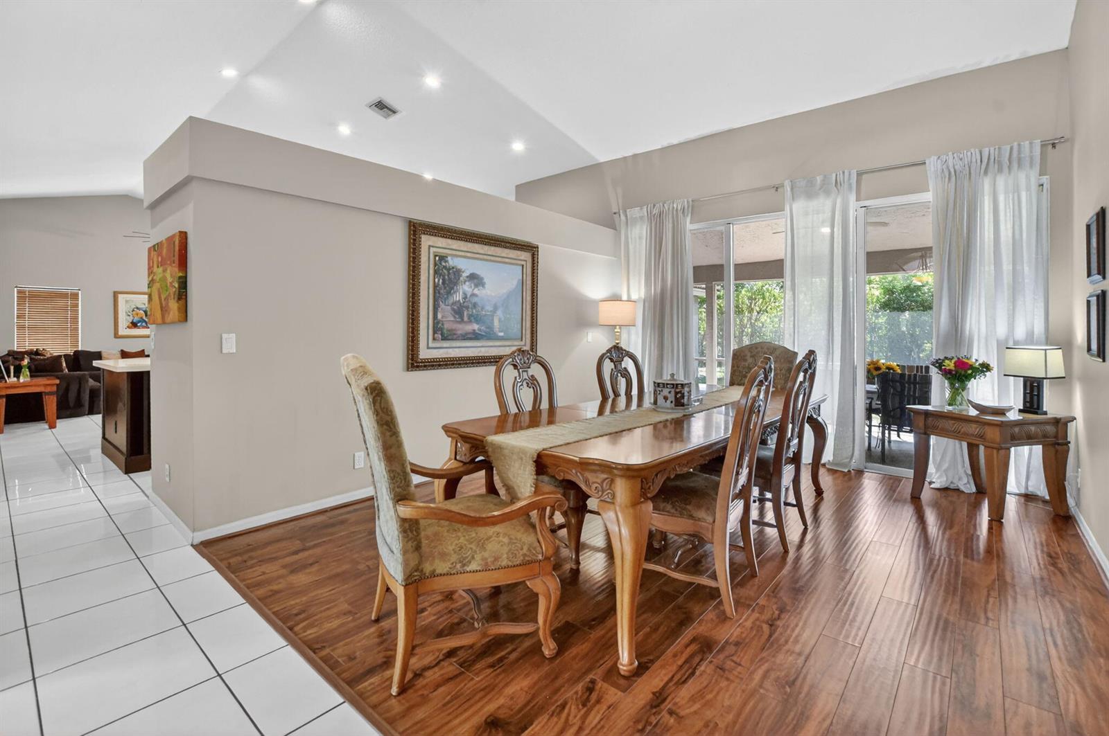 A dining room with a wooden table, upholstered chairs, hardwood floors, and sliding glass doors — 18743 Cape Sable Drive, Boca Raton FL 33498, BOCA RATON, FL