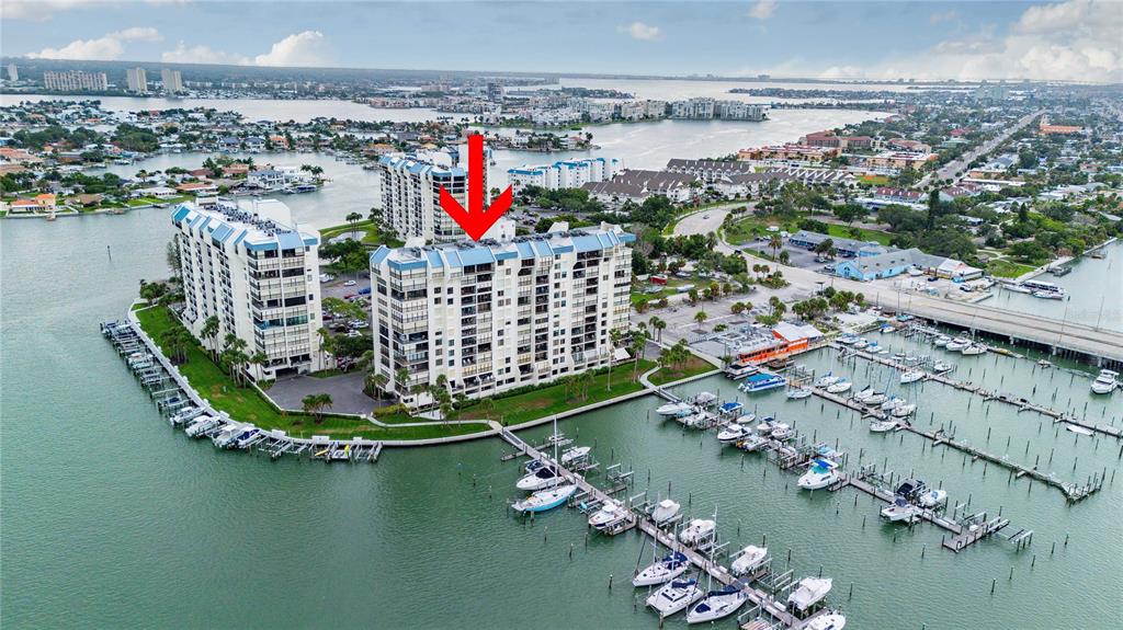 An aerial view shows two waterfront apartment buildings with a marina and docked boats — 9525 BLIND PASS ROAD UNIT 206, ST PETERSBURG, FL