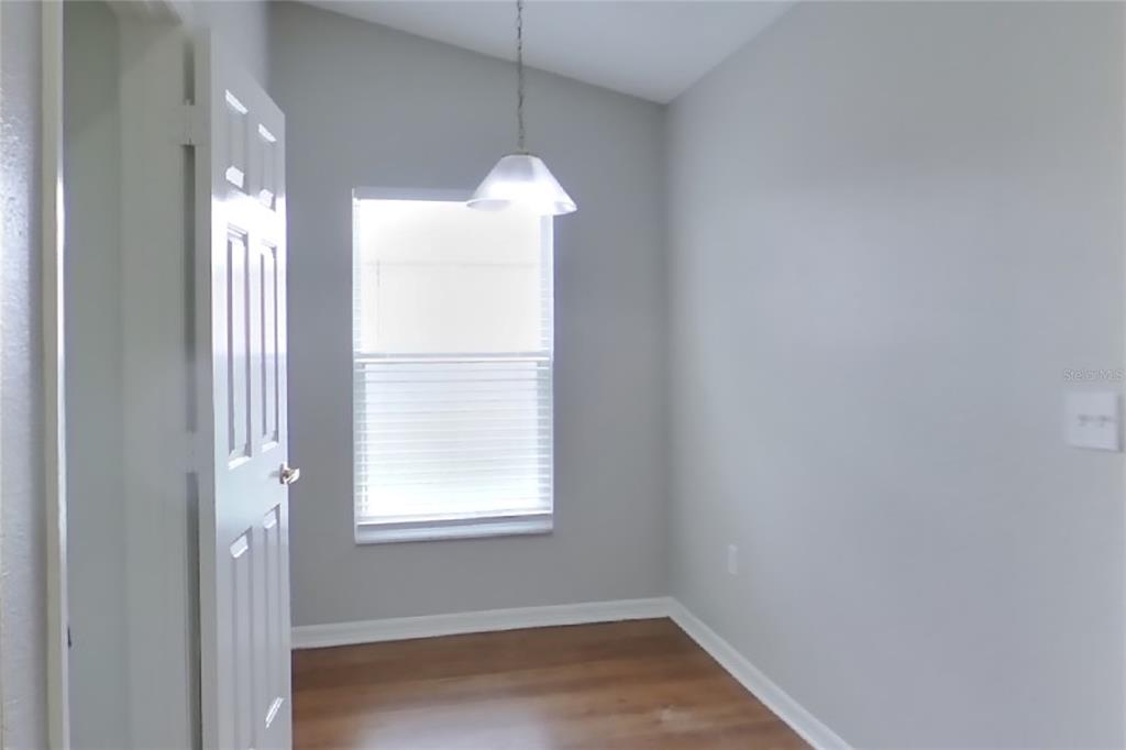 A small room with light gray walls, wood-look flooring, a single window, and a pendant light — 7833 MANOR DRIVE, LAKELAND, FL