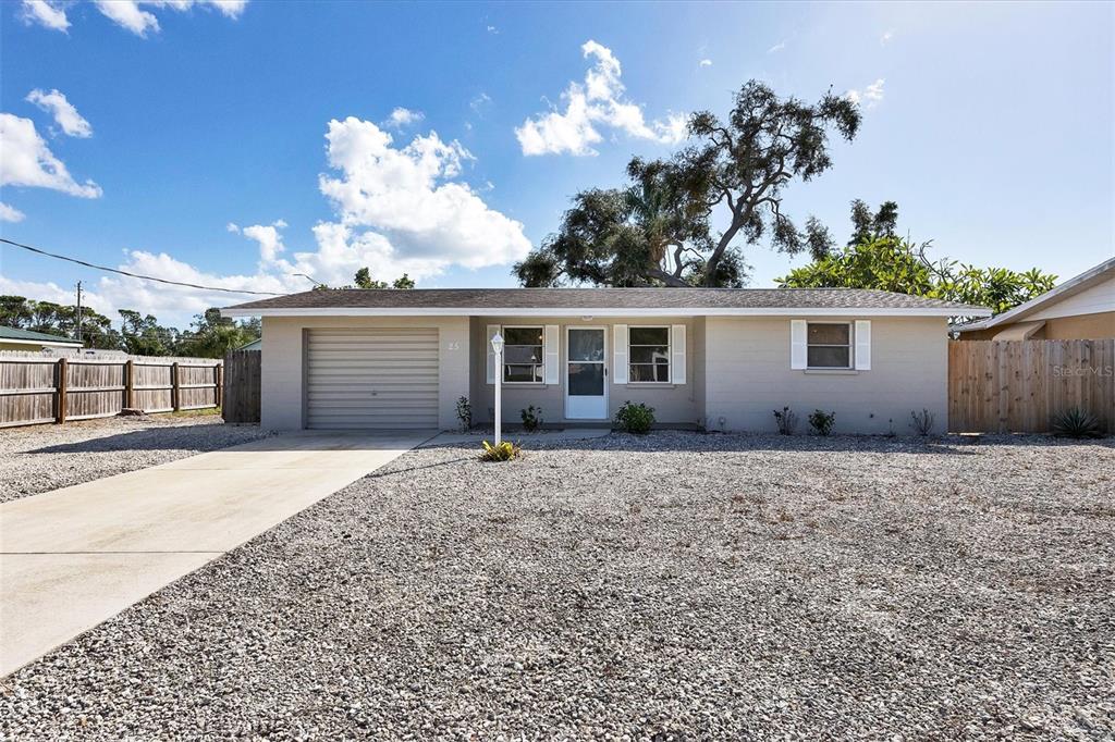 A single-story house with a beige exterior, a gravel front yard, and a concrete driveway — 25 1ST AVENUE, ENGLEWOOD, FL