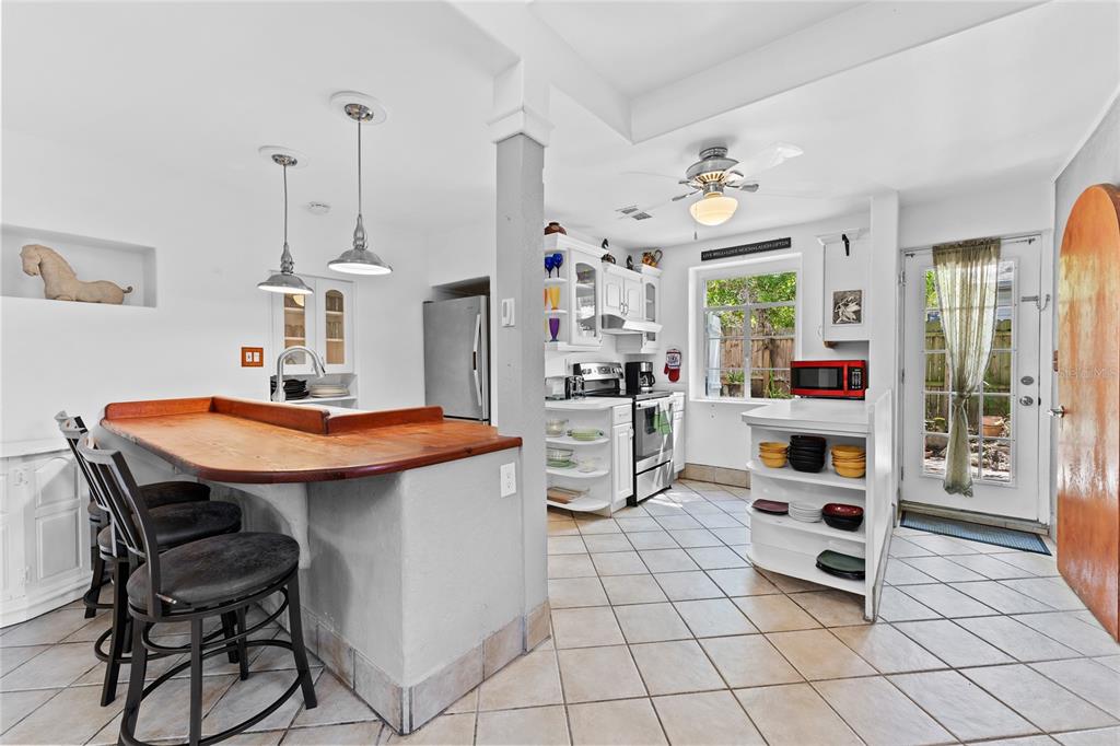 A kitchen features a wooden breakfast bar, white cabinetry, tile flooring, and a glass-paned door — 515 CRYSTAL BEACH AVENUE, CRYSTAL BEACH, FL