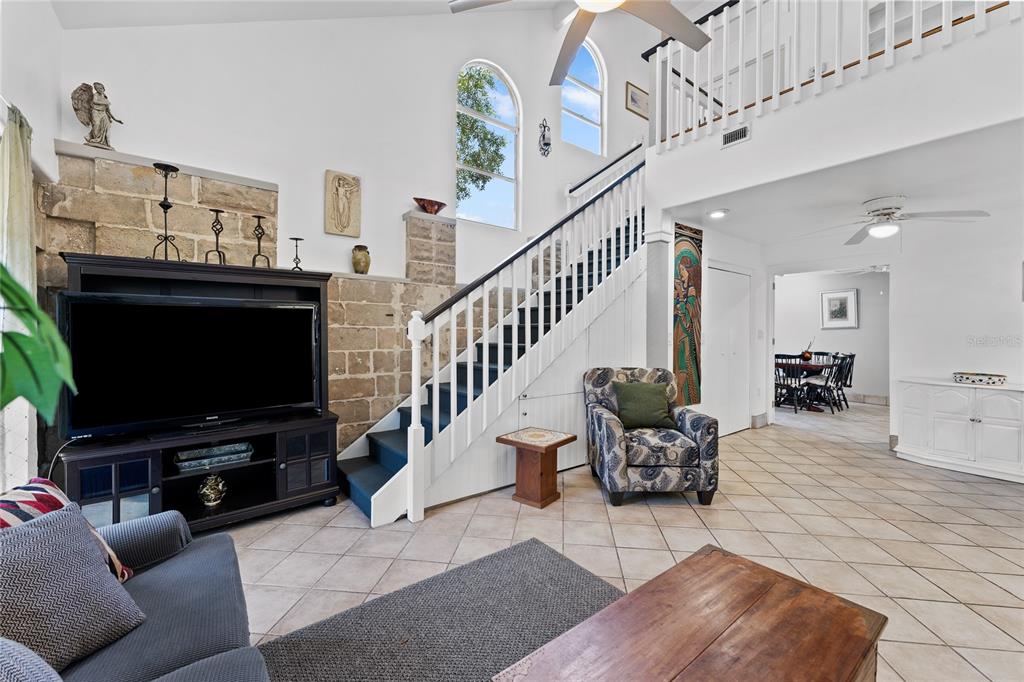 A living room features a stone accent wall, a staircase, and tile flooring — 515 CRYSTAL BEACH AVENUE, CRYSTAL BEACH, FL