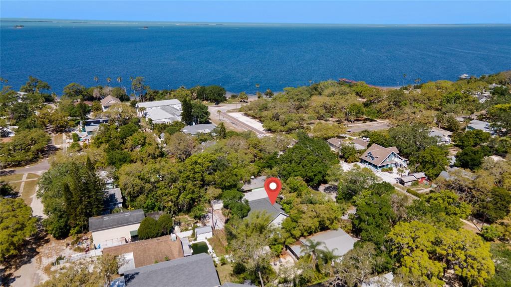 An aerial view shows a house with a red location pin among trees near water — 515 CRYSTAL BEACH AVENUE, CRYSTAL BEACH, FL