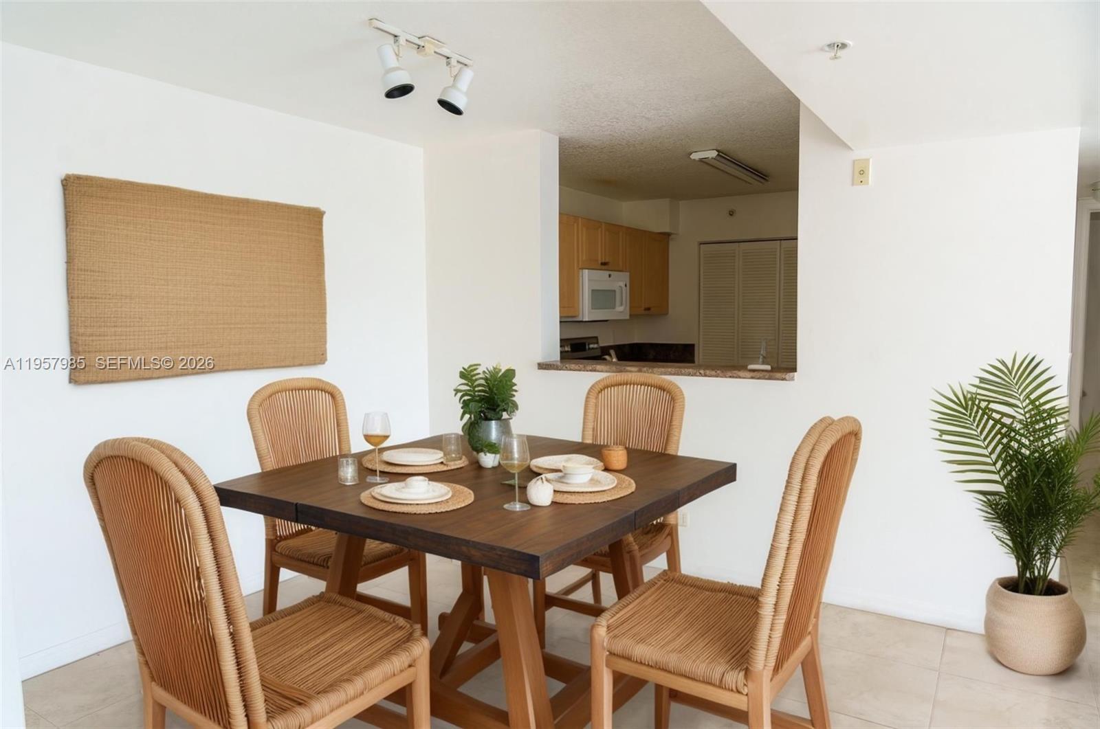 A dining area features a wooden table with four wicker chairs and a pass-through kitchen — 509 E Sheridan St # 3083, Dania Beach FL 33004, DANIA BEACH, FL