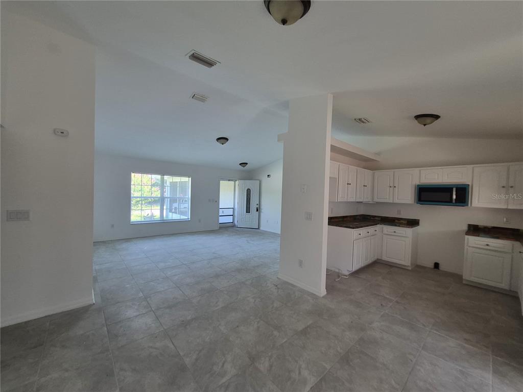 An empty room with gray tile flooring, white walls, and two ceiling light fixtures — 1160 W GENEVA PLACE, CITRUS SPRINGS, FL