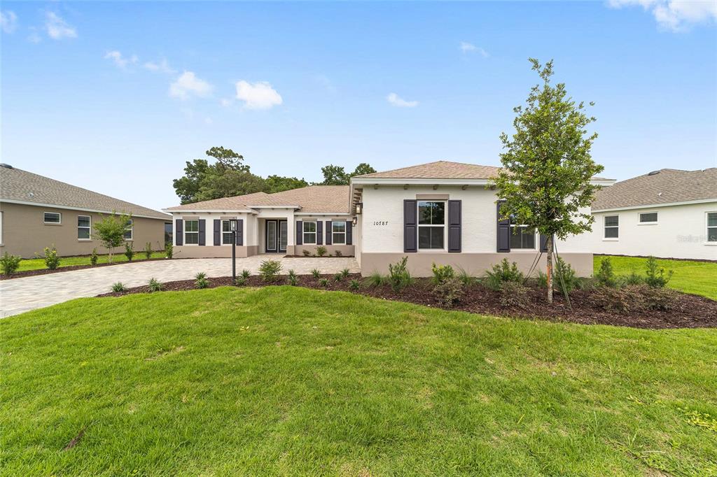 A single-story house with a white exterior, dark shutters, and a paved driveway — 10787 SW 96TH LANE, OCALA, FL