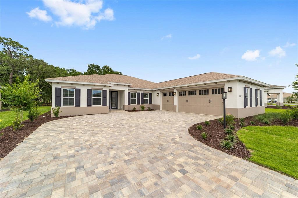 A single-story house with a paved driveway, a three-car garage, and dark window shutters — 10787 SW 96TH LANE, OCALA, FL