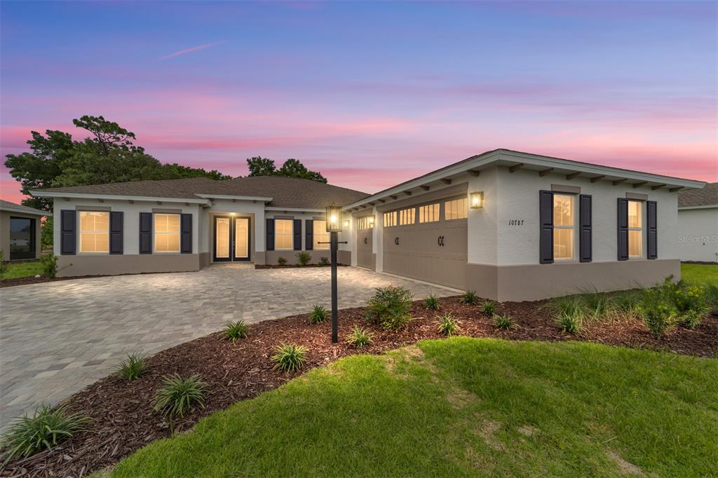 A single-story house with a paved driveway, light-colored stucco exterior, and dark window shutters — 10787 SW 96TH LANE, OCALA, FL