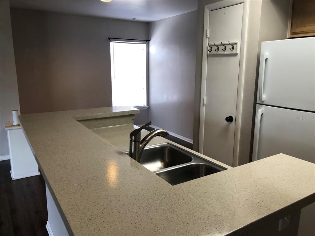 A kitchen features a double-basin sink, a raised breakfast bar, and a white refrigerator — 498 N PIN OAK PLACE UNIT 304, LONGWOOD, FL