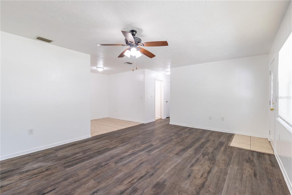 A living room with wood-look flooring, a ceiling fan, and an adjacent tiled dining area — 18 N HARRISON STREET, BEVERLY HILLS, FL