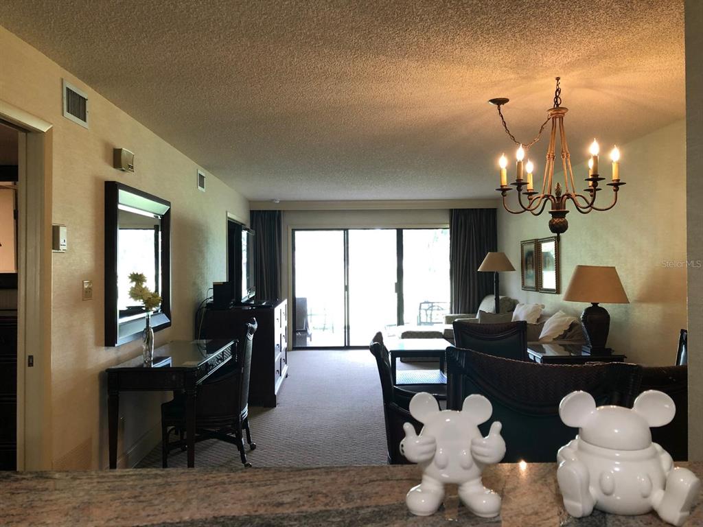A living room with a chandelier, desk, and sliding glass doors leading to a balcony — 29129 BAY HOLLOW DRIVE UNIT 3203, WESLEY CHAPEL, FL
