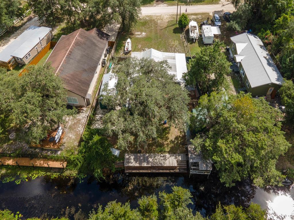 An aerial view shows three houses on a property with a dock along a canal — 24855 NE 135 STREET, SALT SPRINGS, FL
