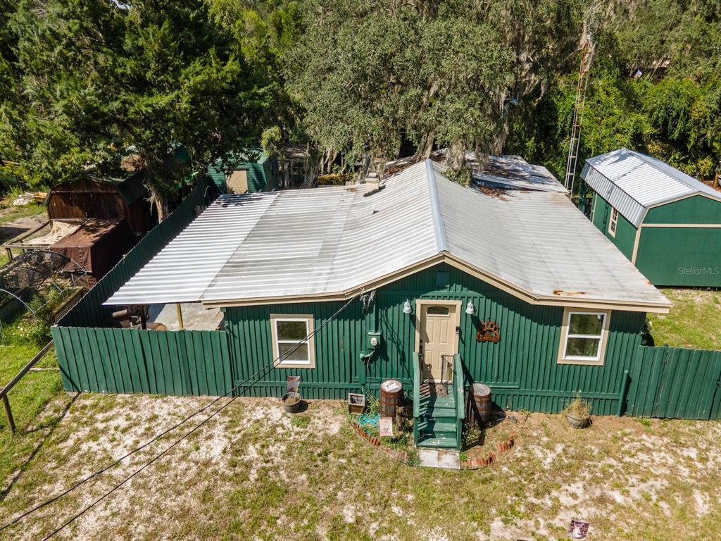 An aerial view of a green house with a metal roof and a fenced yard — 24855 NE 135 STREET, SALT SPRINGS, FL